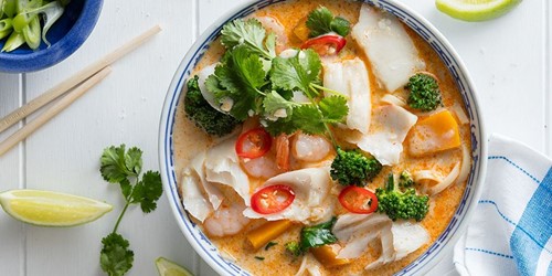 Bowl of dory laksa with coconut broth, noodles, prawns, broccoli, red chilli, and fresh coriander.