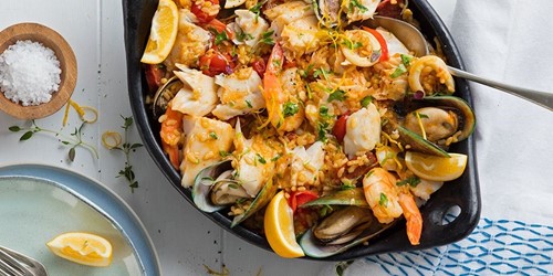 Colourful seafood paella made with Sealord canned tuna, rice, and Mediterranean vegetables served in a black skillet.