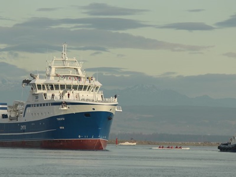Sealord vessel floating on calm water with mountains and a cloudy sky in the background.