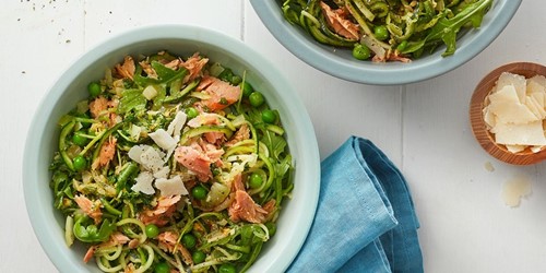 Tuna Zoodle Carbonara in a light blue bowl, featuring flaked tuna, courgette noodles, peas, shaved parmesan, and herbs – a fresh, healthy twist on the classic.