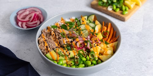 Colourful tuna salad bowl with edamame, cucumber, pineapple, carrot, pickled onion, and black sesame seeds.
