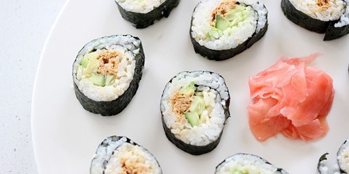 Tuna sushi rolls filled with rice, cucumber, and Sealord lemon sesame ginger tuna, served with pickled ginger on a white plate.