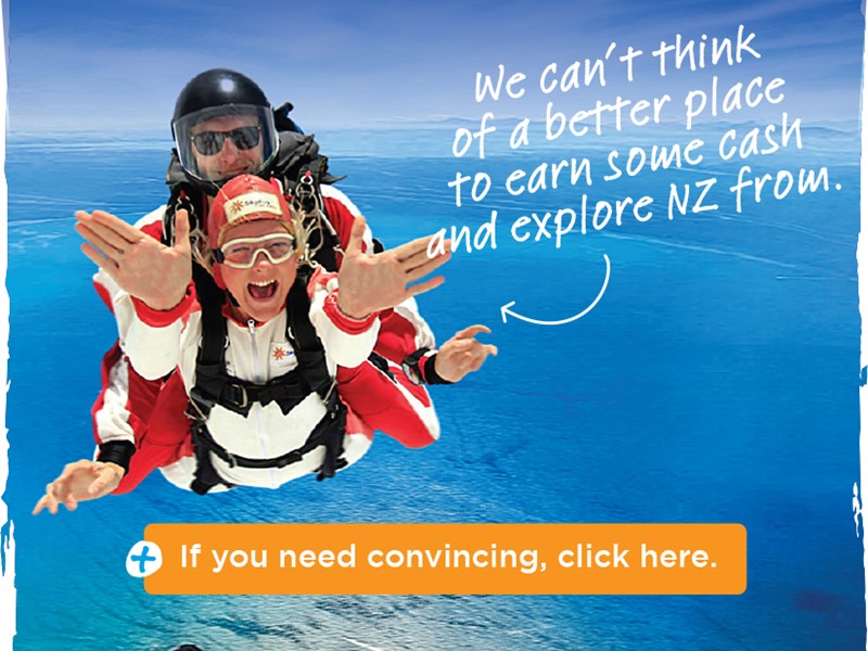 Tandem skydivers smiling and freefalling above bright blue ocean water, with promotional text encouraging work and travel in New Zealand.