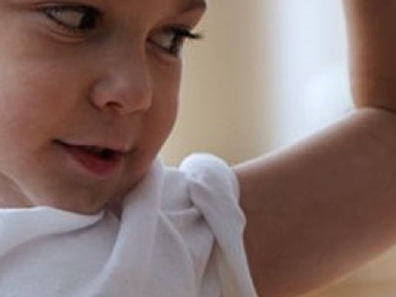 Close-up of a young child smiling and flexing their arm in a playful pose