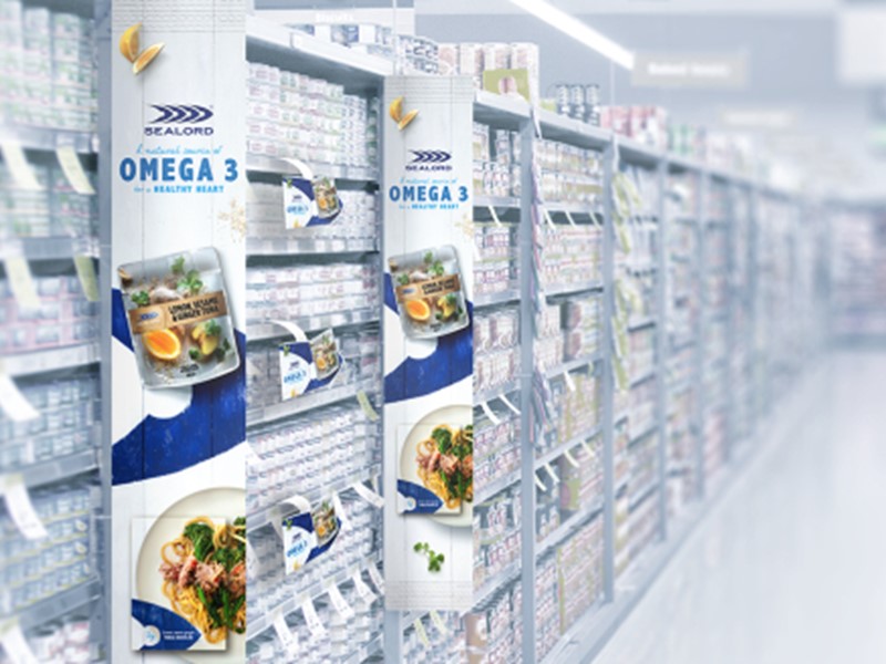supermakert shelf full of sealords products with large promotional banners hanging off the shelves for sealords omgea 3 packed tuna pockets