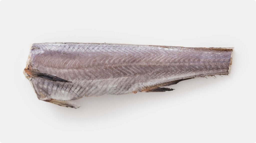 Whole Hoki fish with head, gut, and tail removed (HGT), showing skin-on body with fins intact. Wild-caught and suitable for filleting or export.