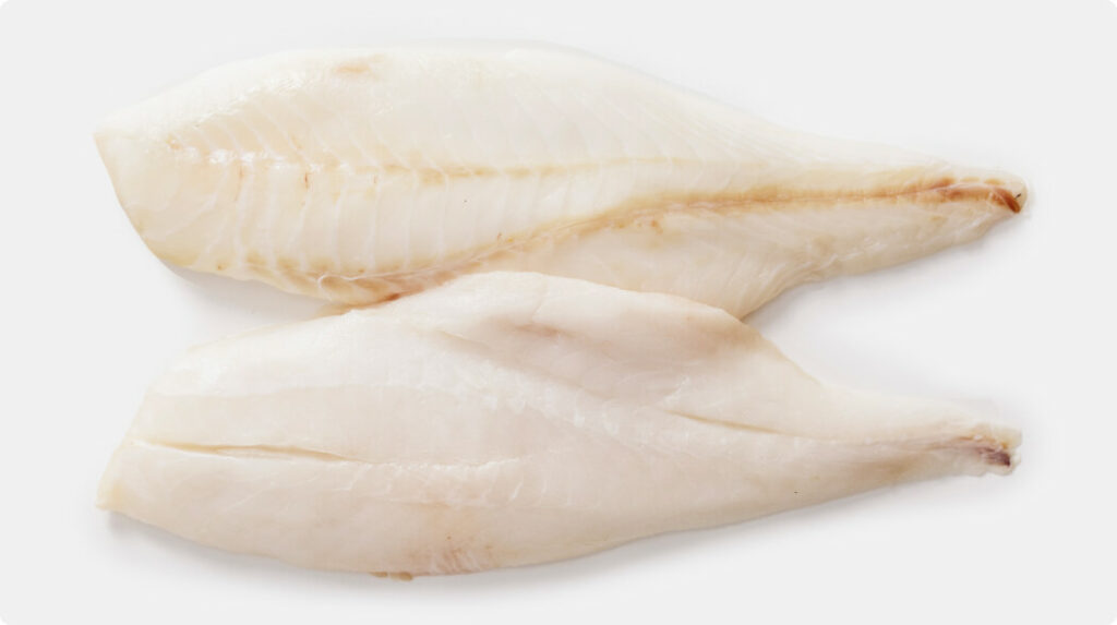 Two raw Orange Roughy fillets, boneless and skinless, with a mild pink-white hue and firm texture.