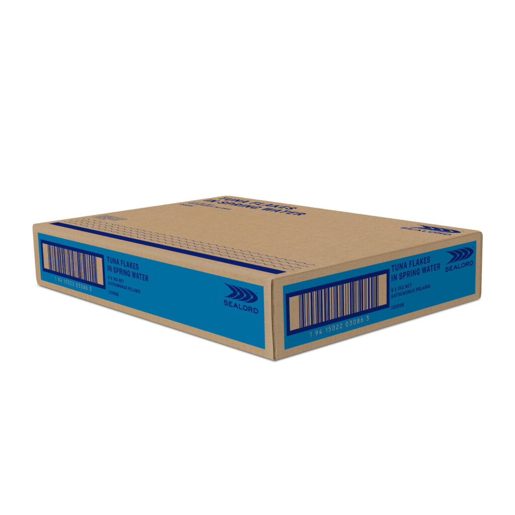 Cardboard carton labeled "Tuna Flakes in Spring Water" by Sealord, featuring blue and navy branding, barcode, and product details printed on the side.